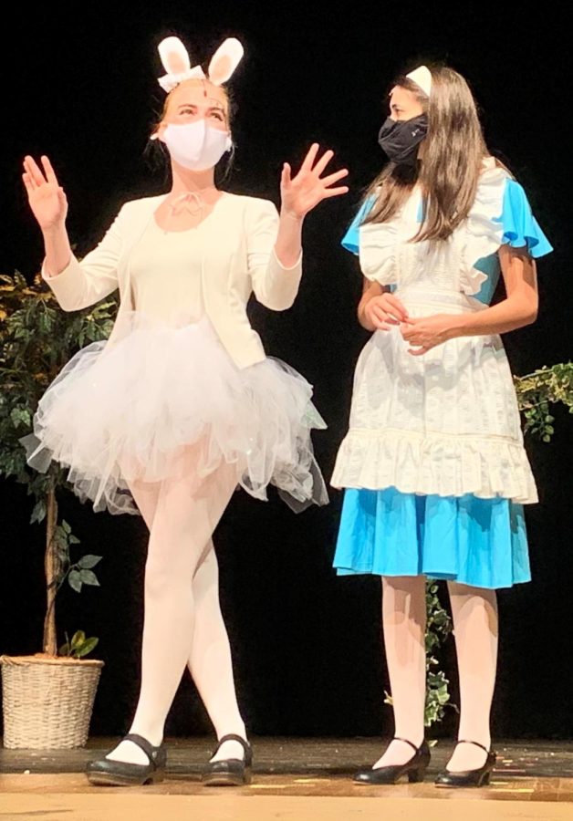 The White Rabbit, played by Nora Brown, holds the attention of Alice, played by Elizabeth Morris. 