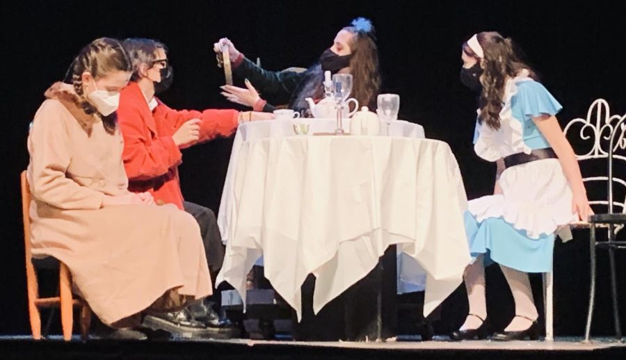 Elizabeth Morris as Alice, right, and Sophia Caneira as the Dormouse, left, look on as Bri Pecks Mad Hatter, center, converses with Tay  Asberrys March Hare during Alice in Wonderland directed by Madelyn Bonkowski. 
